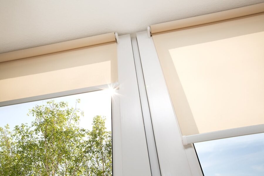 A close-up of two motorized shades lowering over two windows.