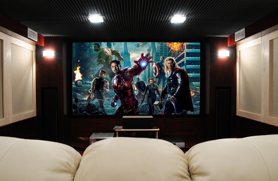 A home theater system and setup featuring seating, acoustic treatments, and a large screen displaying The Avengers (2012)