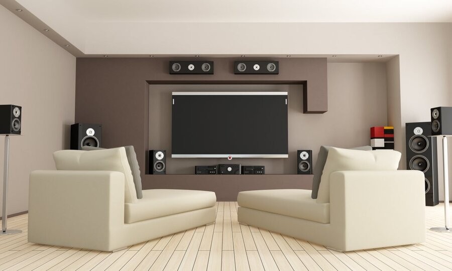 A media room setup featuring a mounted TV and various surround sound speakers.