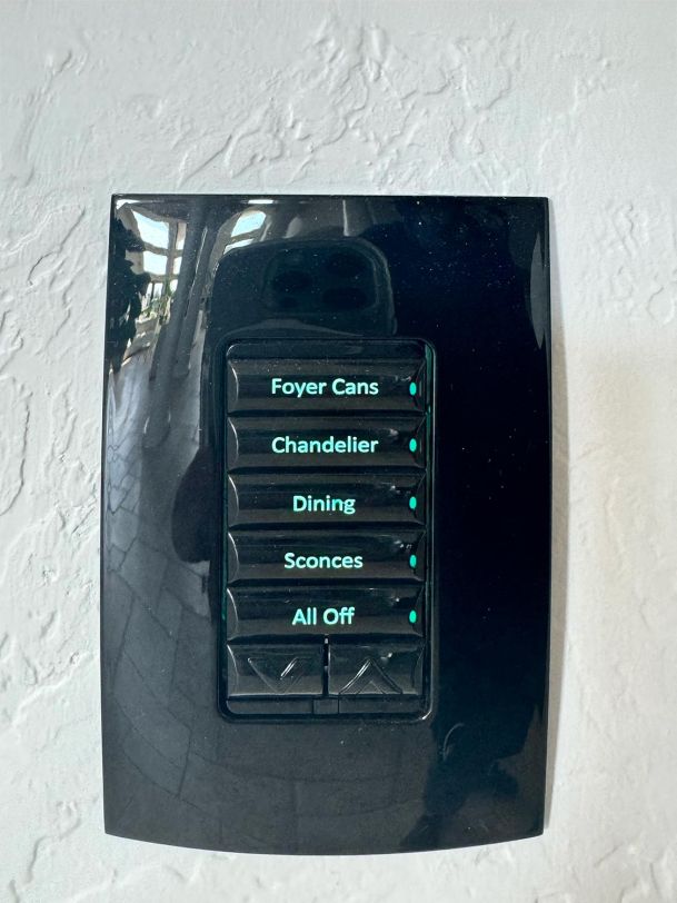 Black wall-mounted control panel with labeled buttons for lighting settings.