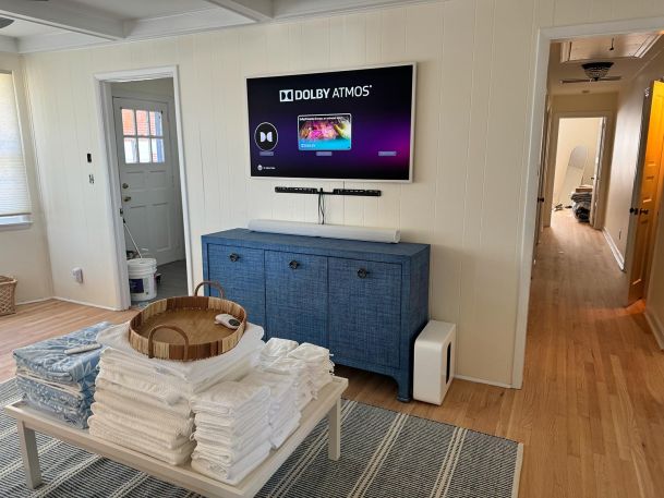 TV setup in a cozy room with a blue cabinet and towels neatly arranged on a center table.