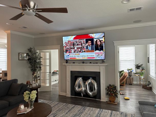 Spacious living room with a large mounted TV above a fireplace and decorative elements around.