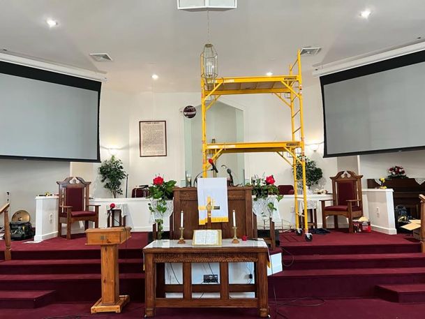 A church stage with scaffolding and large projection screens on both sides of the altar.