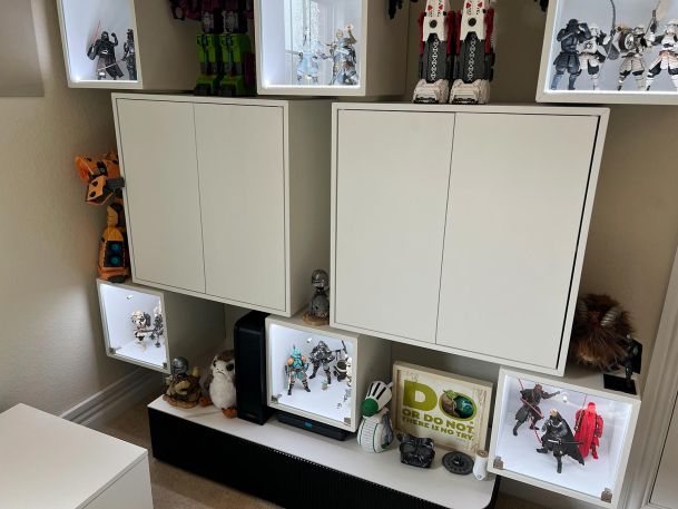 A display cabinet with illuminated cubicles showcasing various collectible action figures.