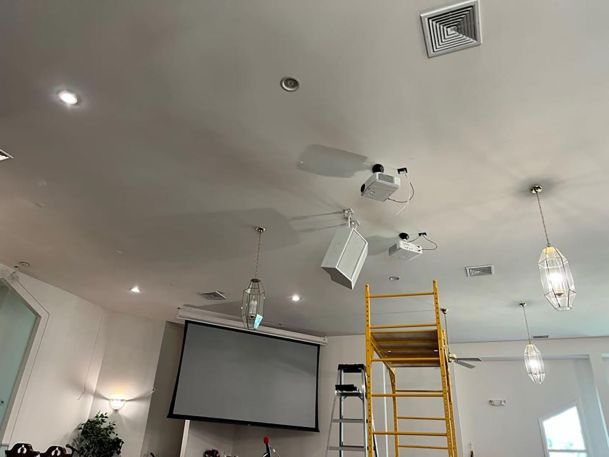 A ceiling view of a church featuring projectors, lights, and a speaker system with scaffolding.