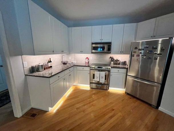 A modern kitchen with stainless steel appliances and under-cabinet lighting.