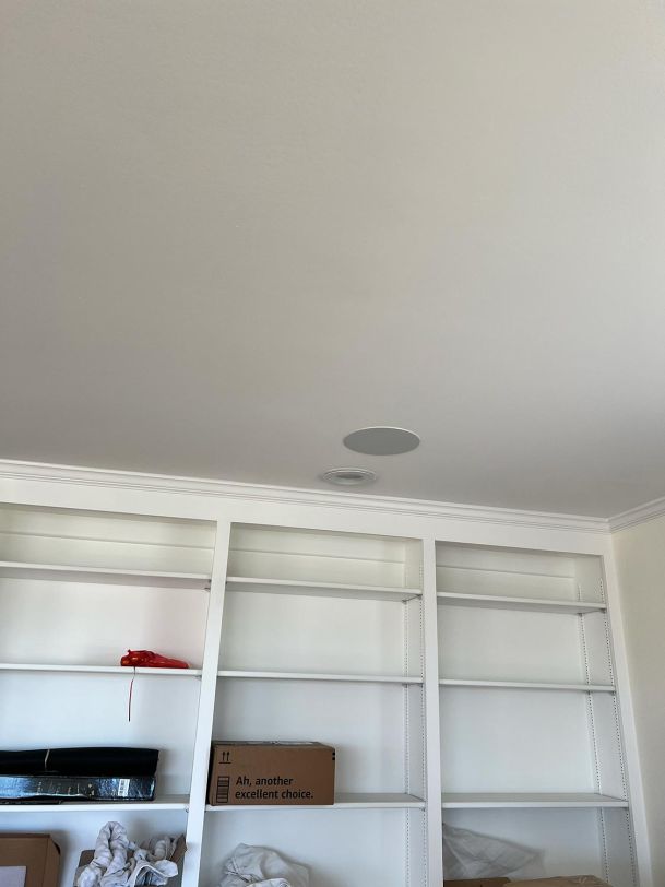 A built-in bookshelf with empty shelves and a ceiling speaker visible above.